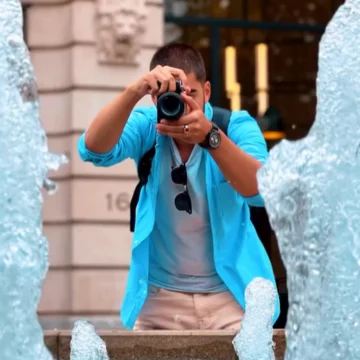 a man taking a picture of a fountain